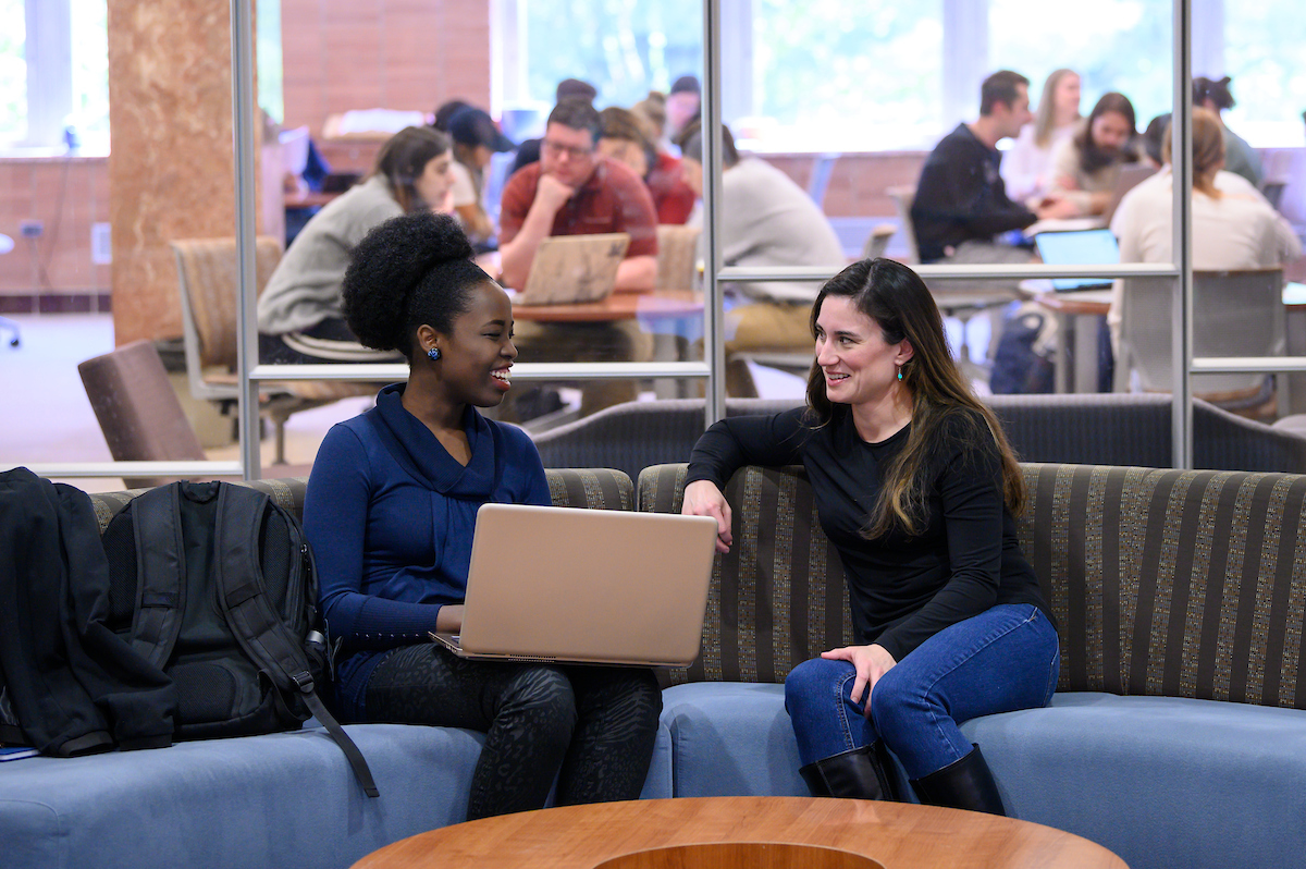 Two graduates students in library share a laugh